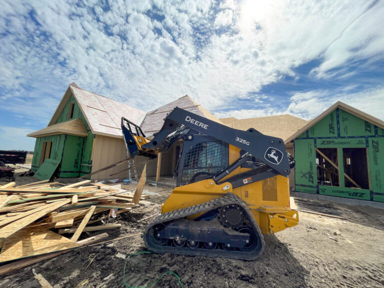 Skid steer clearing lumber at a home framing and construction site