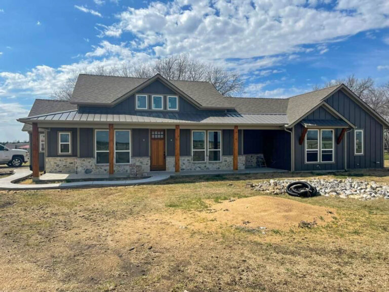 Blue-gray farmhouse custom home with a metal porch roof and cedar posts