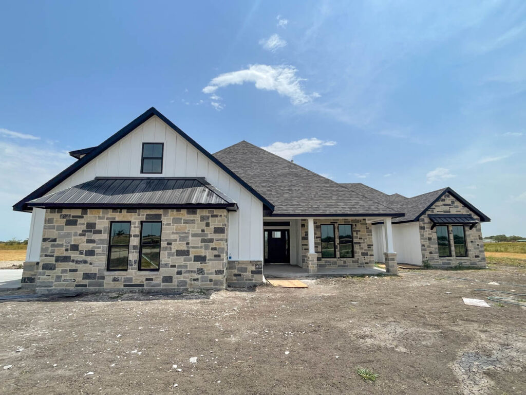 Custom home with a stone front and white board-and-batten gables