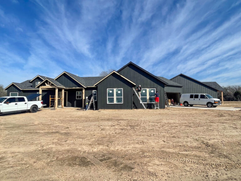 New dark board-and-batten custom home on a freshly graded lot