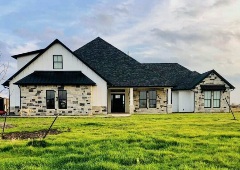 Custom home with a stone and white siding exterior and dark roof