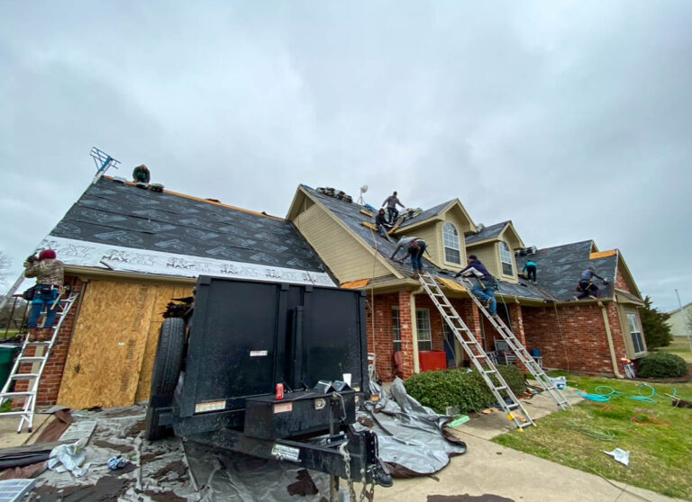 Roof replacement in progress on a two-story home with a dumpster trailer