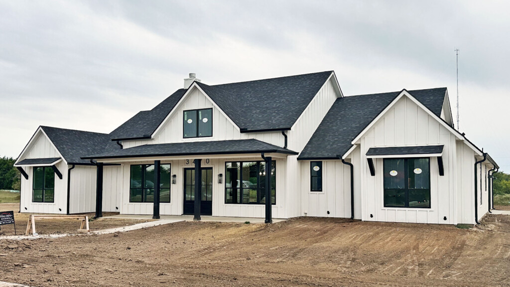 Newly built white modern farmhouse with multiple gables and black-framed windows