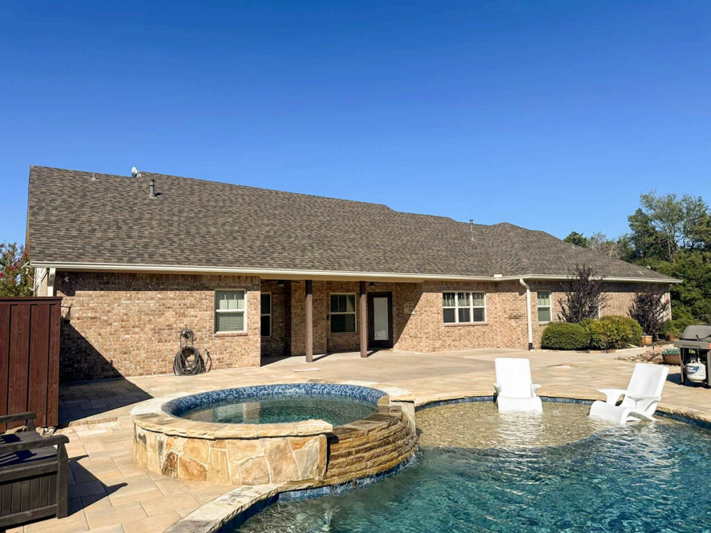 Brick home backyard with a new pool and raised spa