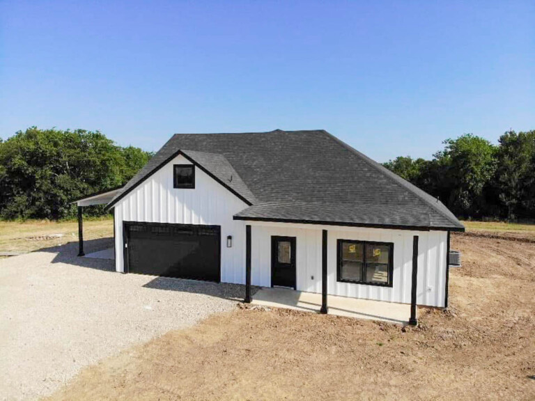 New white board-and-batten home with an attached garage under construction cleanup