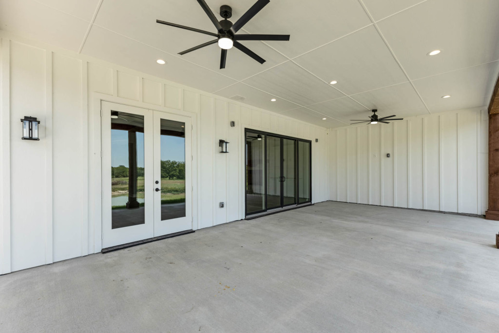 Covered porch with white board-and-batten walls, French doors and ceiling fan
