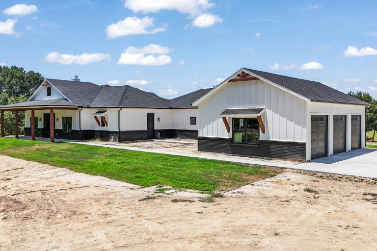 White farmhouse-style home with a matching detached garage on a rural lot