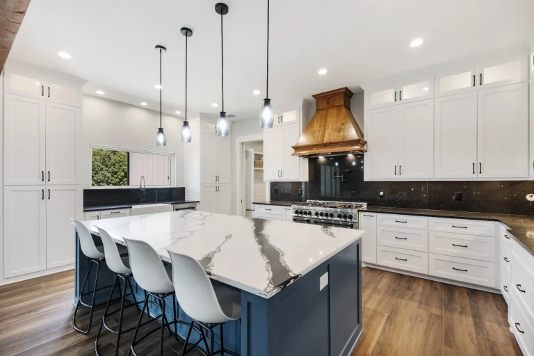 Blue kitchen island with seating and black pendant lights