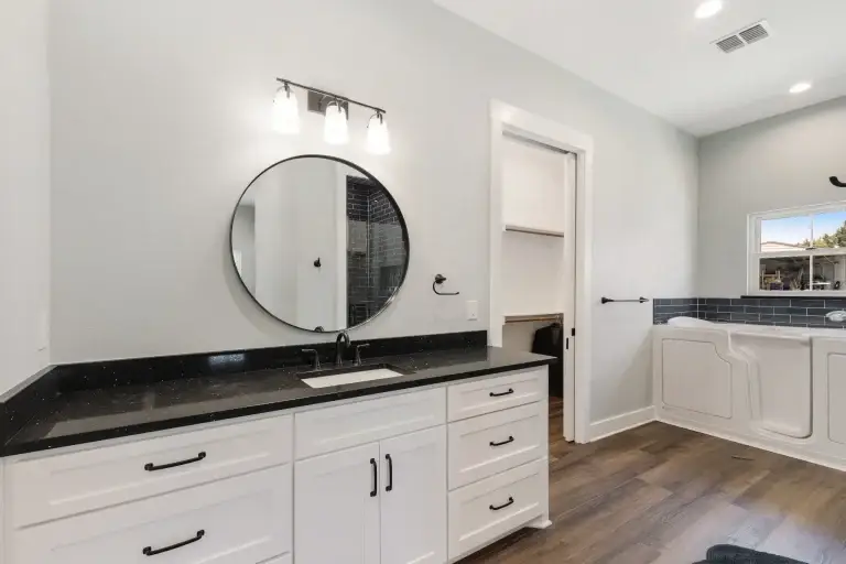 Bathroom with round mirror and black vanity top