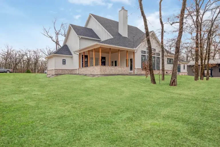 Rear covered porch of the farmhouse among mature oaks