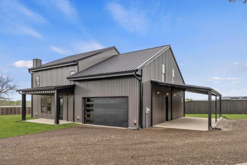 Charcoal steel barndominium in Greenville with covered carports and a black garage door
