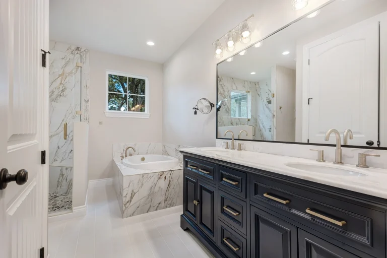 Primary bath with navy double vanity and soaking tub